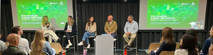 Photo from Climate Week Zurich showing a panel discussion with five speakers seated on stage before Picterra presentation slide on climate risk and supply chain resilience, with an audience listening in the foreground.